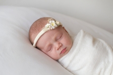 baby photographed on white with small white tieback